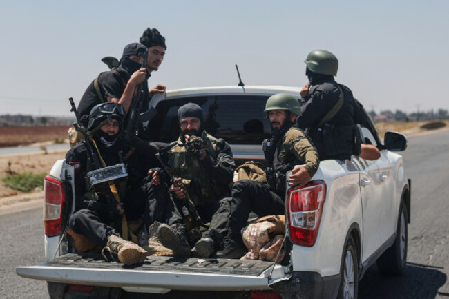 syrian-security-forces-ride-in-the-back-of-a-pickup-truck-on-the-international-highway-near-izraa-in-rural-daraa-province-syria-saturday-july-19-2025-ap-photoghaith-alsayed
