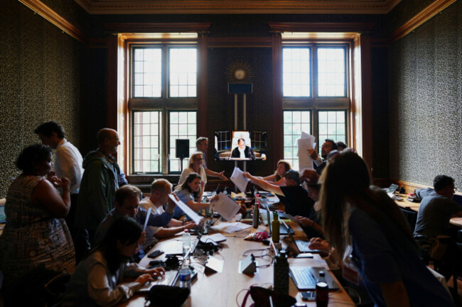 journalists-scramble-to-get-a-copy-of-the-readings-as-presiding-judge-yuji-iwasawa-can-be-seen-speaking-onscreen-at-the-international-court-of-justice-for-an-advisory-opinion-on-what-legal-obligations