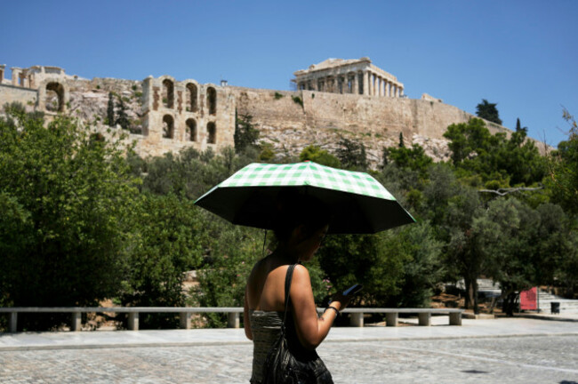 a-tourist-holding-an-umbrella-against-the-sun-passes-by-the-acropolis-hill-which-remained-closed-for-five-hours-due-the-new-heat-wave-in-athens-greece-thursday-july-24-2025-ap-photothanassis-st