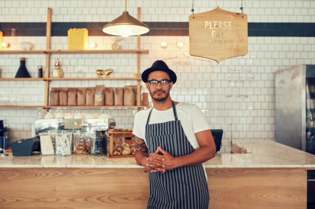 portrait-of-a-confident-young-coffee-shop-owner-standing-at-the-cafe-counter-handsome-young-man-working-at-a-restaurant-and-wea