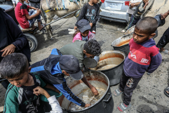 khan-younis-gaza-12th-may-2025-palestinian-children-try-to-collect-leftover-food-from-a-distribution-site-operated-by-a-charity-providing-hot-meals-to-palestiniansn-the-al-mawasi-area-of-khan-yuni