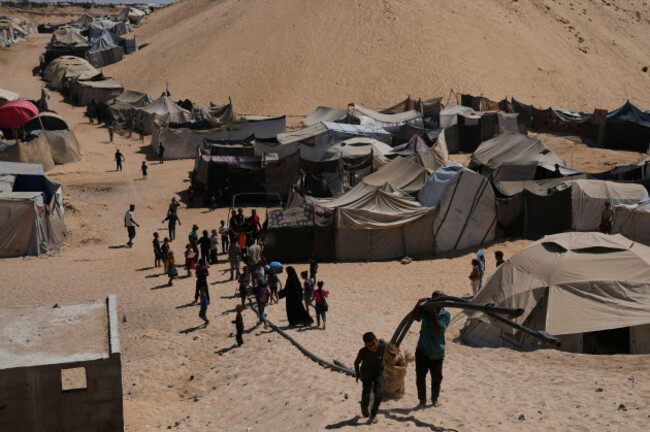 displaced-palestinians-walks-through-a-tent-camp-in-muwasi-an-area-that-israel-has-designated-as-a-safe-zone-in-khan-younis-southern-gaza-strip-sunday-sept-21-2025-ap-photojehad-alshrafi