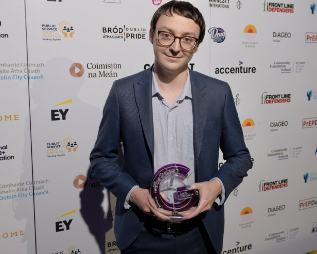 Conor wearing a suit holding a glass trophy.