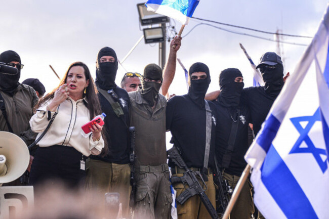 knesset-member-revital-tally-gotliv-gives-a-supportive-speech-for-the-100-force-reservists-detainees-as-their-friends-from-the-unit-stand-next-to-her-armed-and-masked-israeli-right-wing-activists