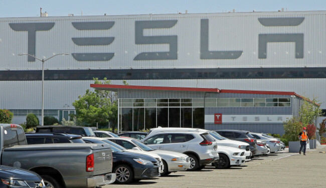 file-in-this-monday-may-11-2020-file-photo-a-man-wearing-a-mask-walks-through-the-tesla-plant-parking-lot-in-fremont-calif-on-wednesday-july-22-2020-the-electric-car-maker-announced-it-has-p