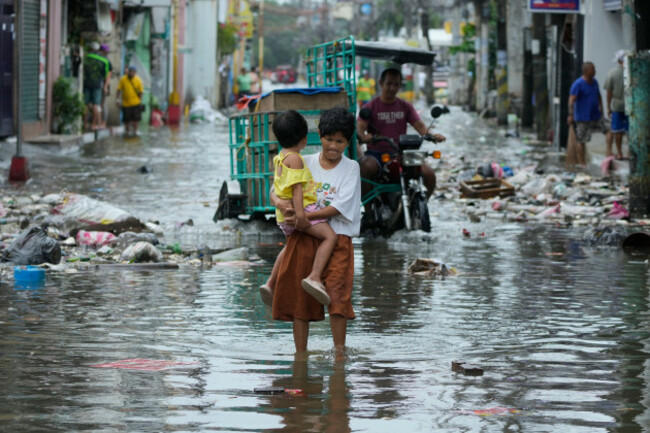 a-woman-and-child-crosses-a-flooded-street-due-to-typhoon-fung-wong-and-high-tide-on-monday-nov-10-2025-in-navotas-philippines-ap-photoaaron-favila