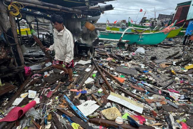 a-man-walks-on-debris-washed-ashore-due-to-typhoon-fung-wong-along-a-coastal-village-on-monday-nov-10-2025-in-navotas-philippines-ap-photoaaron-favila