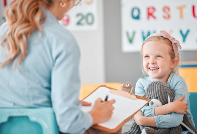 smiling-little-girl-with-social-worker-in-a-clinic-child-psychologist-writing-on-a-clipboard-during-consult-with-adorable-kid-caucasian-woman