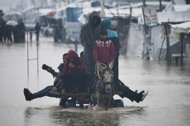 palestinians-cross-a-flooded-street-following-heavy-rain-in-khan-younis-southern-gaza-strip-thursday-dec-11-2025-ap-photoabdel-kareem-hana