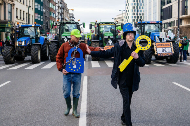 two-men-walk-in-front-of-tractors-during-a-demonstration-of-european-farmers-outside-the-eu-summit-meeting-in-brussels-thursday-dec-18-2025-ap-photomarius-burgelman