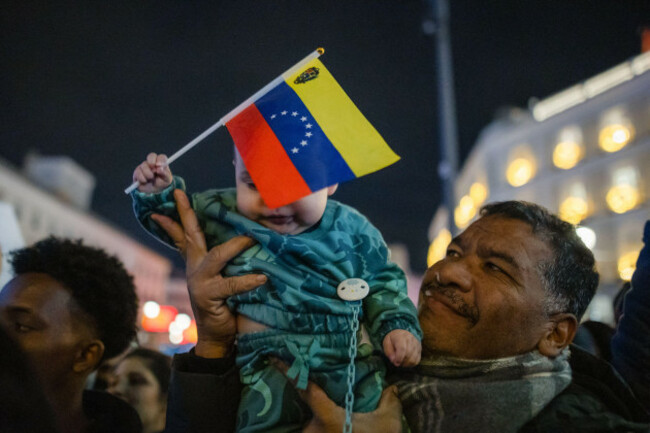 madrid-spain-03rd-jan-2026-a-man-carries-a-baby-in-his-arms-his-face-covered-by-a-venezuelan-flag-during-a-rally-venezuelans-living-in-madrid-celebrated-in-the-city-center-after-us-president-do