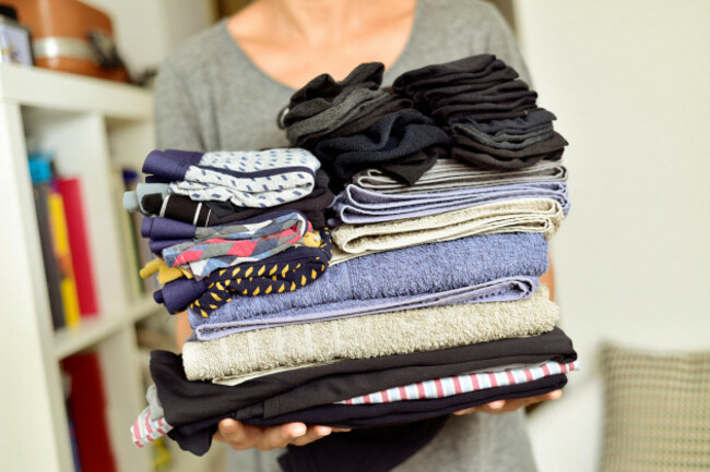 closeup-of-a-young-man-carrying-a-pile-of-different-folded-clothes
