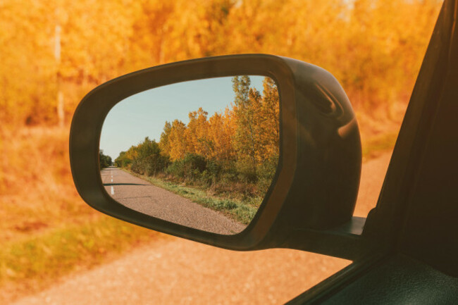 autumn-scenery-in-car-rear-view-mirror-driving-through-forest-in-fall-selective-focus