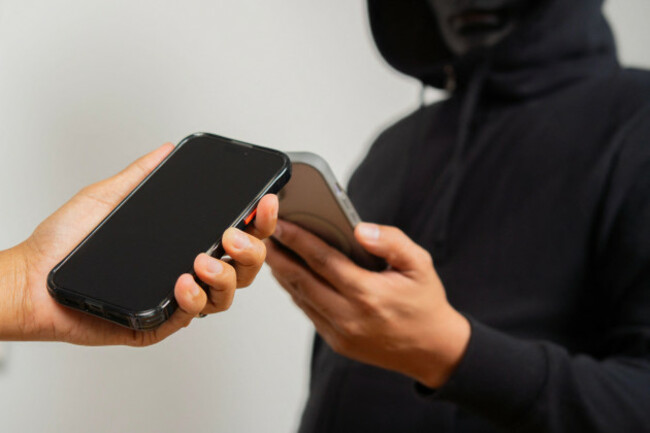 phone-in-hand-holding-with-man-in-black-mask-cybercrime-concept-criminal-on-phone-fraud-scam-threatening-call-extortion-robbery-theft-financi