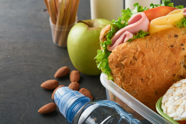healthy-food-for-school-lunch-concept-healthy-bread-meat-sandwich-with-cheese-apple-fresh-cucumber-carrots-nuts-in-container-water-and-yogurt-on-dark-background-back-to-school-concept