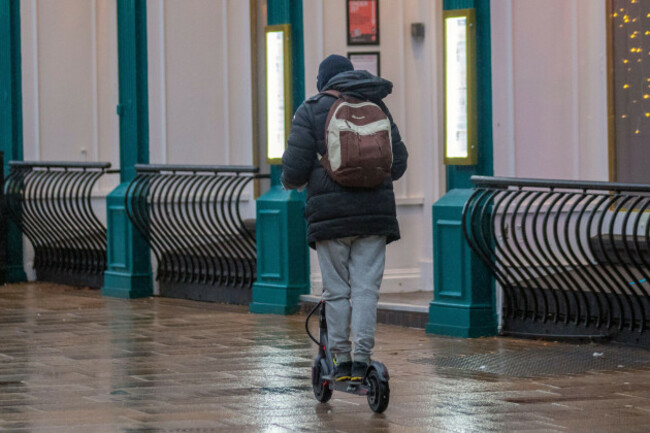 man-riding-an-electric-bike-on-the-pavement-preston-lancashire-uk-weather-28-dec-2021-festive-shop-sales-shoppers-shopping-on-a-wet-day-in-preston-muted-reaction-to-post-christmas-fashion-sales