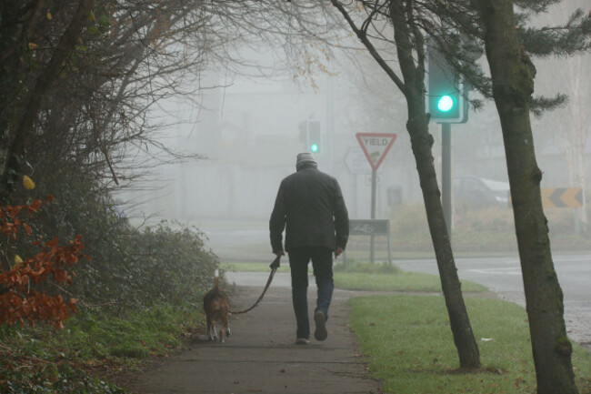dublin-ireland-december-26th-2024-a-man-walks-his-dog-in-an-urban-street-scene-of-heavy-fog-over-south-dublin-ireland-heavy-fog-covers-dublin-o