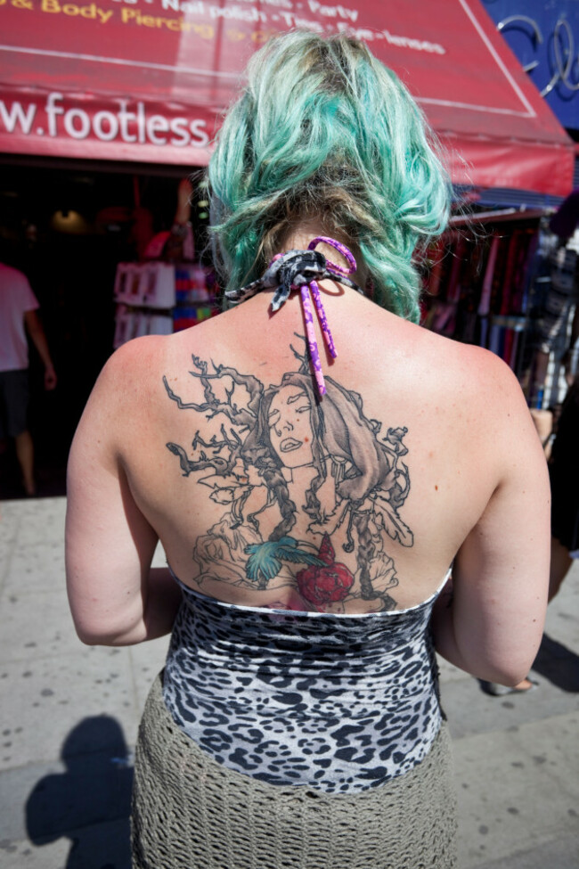 rear-angle-view-of-a-trendy-woman-with-a-large-tattoo-covering-her-back-camden-town-london-england-uk
