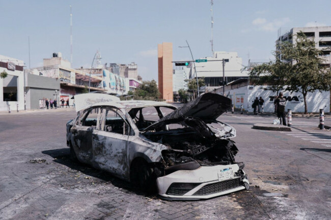 a-vehicle-sits-charred-after-being-set-on-fire-on-a-road-in-guadalajara-jalisco-state-mexico-sunday-feb-22-2026-after-the-death-of-the-leader-of-the-jalisco-new-generation-cartel-nemesio-rube