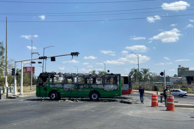 pedestrians-walk-past-charred-buses-that-were-set-on-fire-on-a-road-in-guadalajara-jalisco-state-mexico-sunday-feb-22-2026-after-the-death-of-the-leader-of-the-jalisco-new-generation-cartel-n
