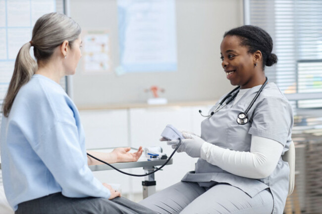young-adult-caucasian-woman-having-blood-pressure-checked-by-black-nurse