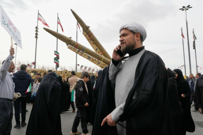 a-cleric-talks-on-his-phone-as-he-walks-in-front-of-domestically-built-missiles-during-an-annual-rally-marking-1979-islamic-revolution-at-the-azadi-or-freedom-square-in-tehran-iran-wednesday-feb