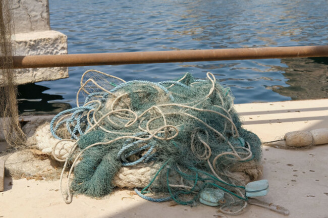 braided-fishing-net-from-fibers-woven-in-a-grid-like-structure-with-floats-pile-of-fish-mesh-traps-on-the-pier