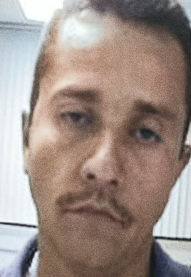 a-grainy-colorized-portrait-from-the-2010s-shows-a-man-identified-as-nemesio-oseguera-cervantes-known-as-el-mencho-staring-directly-at-the-viewer-he-has-a-prominent-mustache-and-a-serious-expres