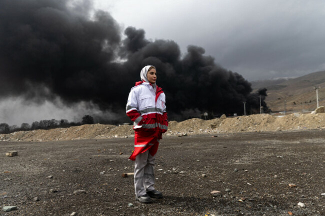 tehran-iran-08th-mar-2026-an-iranian-red-crescent-volunteer-stands-in-front-of-the-shahran-oil-depot-which-was-targeted-by-u-s-israeli-strikes-on-the-eighth-day-of-the-war-in-western-tehran-ir