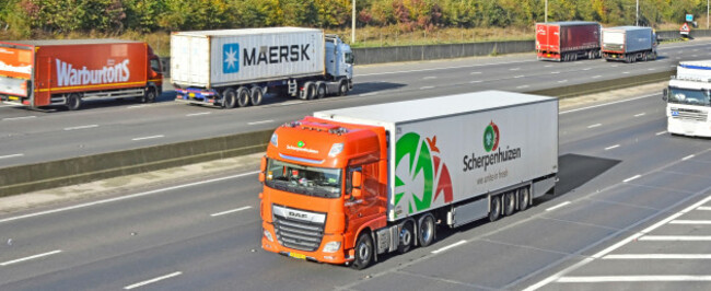 mobile-advertising-brands-business-names-on-side-of-large-european-commercial-vehicles-driving-alone-m25-motorway-road-in-county-of-essex-england-uk