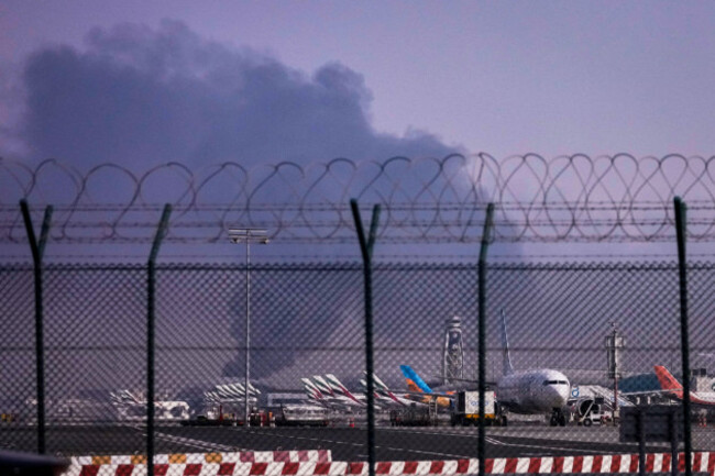 planes-are-parked-at-dubai-international-airport-as-smoke-rises-in-the-background-after-a-drone-struck-a-fuel-tank-early-morning-forcing-the-temporary-suspension-of-flights-in-dubai-united-arab-emi