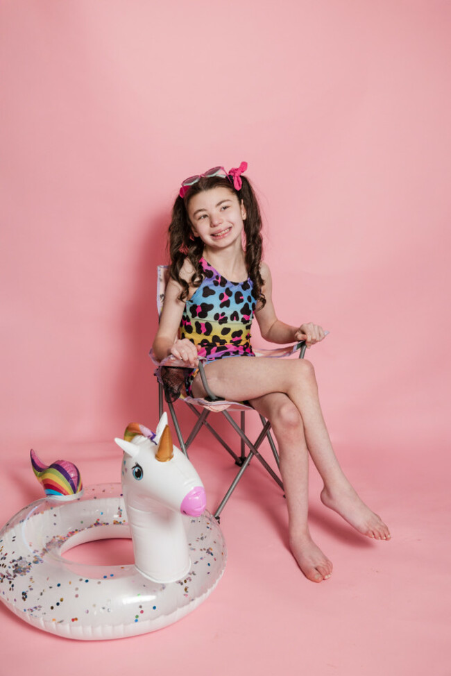 A smiling Lucy sits in her Born Zippy swimsuit which features matching reusable swim nappy protection