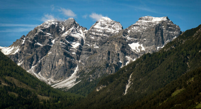 snow-capped-mountain-peaks-with-forested-slopes-under-a-blue-sky