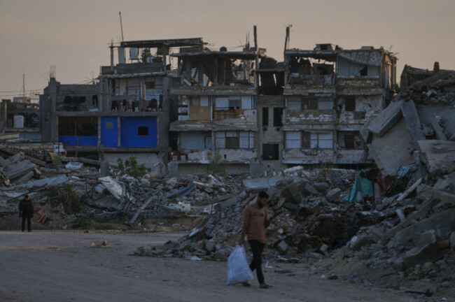 palestinians-walk-along-a-street-surrounded-by-buildings-destroyed-during-israeli-air-and-ground-operations-in-khan-younis-southern-gaza-strip-thursday-april-9-2026-ap-photoabdel-kareem-hana