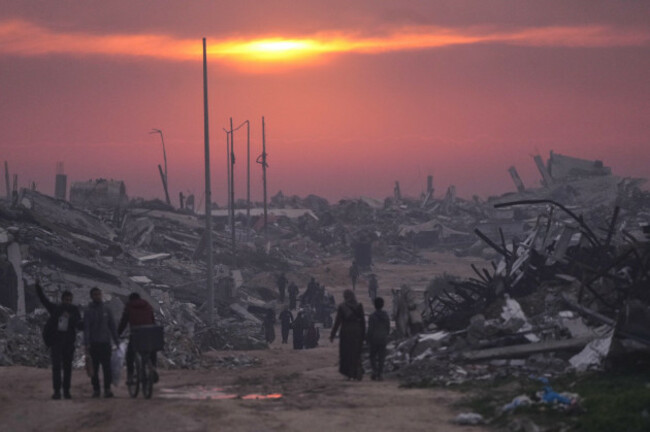 file-palestinians-walk-through-the-ruins-of-destroyed-buildings-as-the-sun-sets-over-gaza-city-sunday-jan-4-2026-ap-photojehad-alshrafi-file