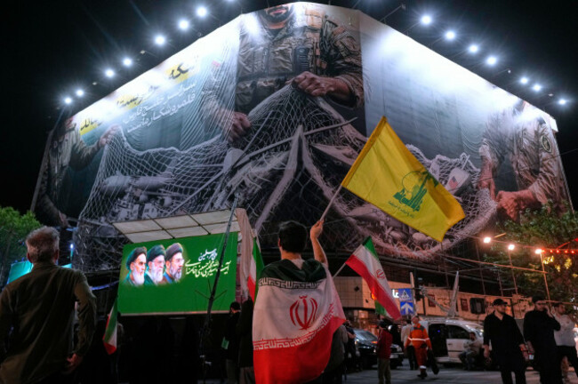 an-iranian-demonstrator-waves-a-flag-of-lebanons-militant-hezbollah-group-under-an-anti-u-s-billboard-depicting-the-american-aircrafts-into-the-iranian-armed-forces-fishing-net-with-signs-that-read