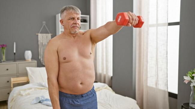 middle-aged-man-exercising-with-dumbbell-in-a-bedroom-setting-showcasing-a-fitness-lifestyle-at-home
