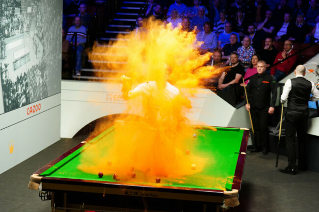a-just-stop-oil-protester-jumps-on-the-table-and-throws-orange-powder-during-the-match-between-robert-milkins-against-joe-perry-during-day-three-of-the-cazoo-world-snooker-championship-at-the-crucible