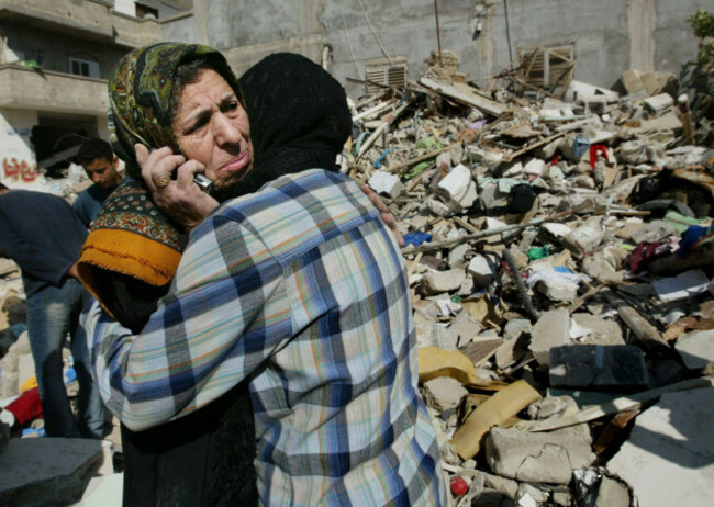 palestinian-women-from-the-awad-family-embrace-as-one-speaks-to-relatives-on-a-mobile-phone-as-they-weep-in-front-of-their-destroyed-house-in-the-brazil-section-of-the-rafah-refugee-camp-southern-gaz