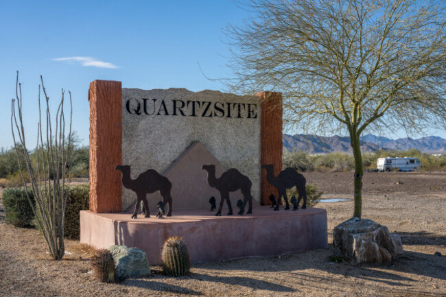 the-sign-at-the-city-limits-of-quartzsite-arizona-with-the-dome-rock-mountains-behind