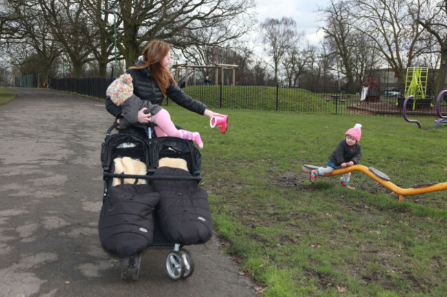 young-mum-walking-in-the-park-pushing-a-twin-buggy-with-her-twin-toddlers