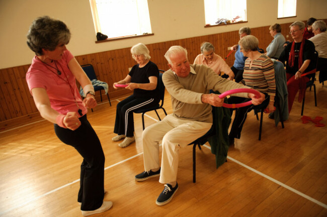 a-group-of-fit-active-senior-citizens-participating-in-low-impact-chair-aerobics-class-in-a-small-village-hall-in-west-wales-uk