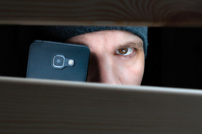 information-leak-recording-to-a-hidden-camera-on-mobile-private-detective-with-camera-looks-at-a-cleft-espionage-background-the-concept-of-eavesdropping-espionage-gossip-and-the-yellow-press