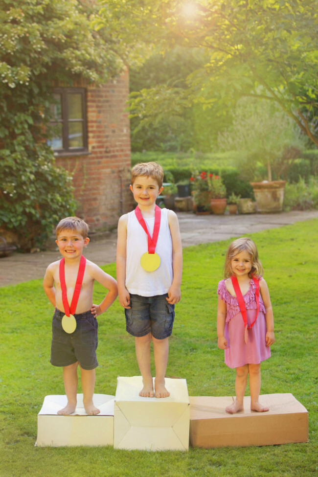 children-standing-on-cardboard-podium-with-medals