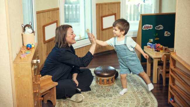 teacher-and-toddler-giving-high-five-in-montessori-classroom-with-joyful-learning-mood