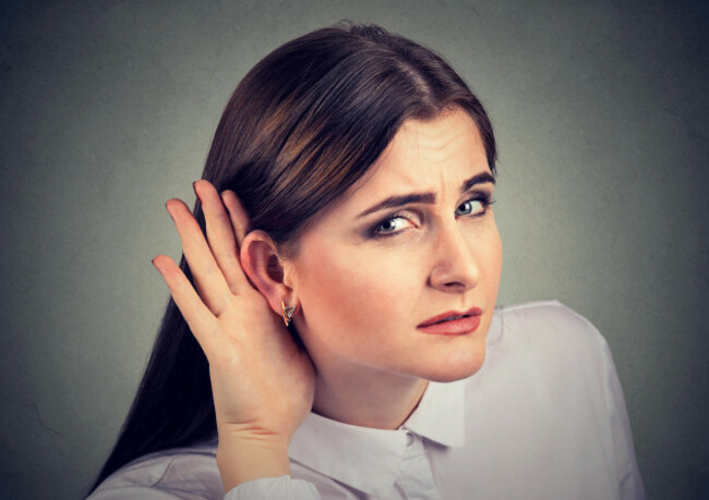 woman-with-a-hearing-loss-cupping-her-hand-behind-ear-with-her-head-turned-towards-camera-to-try-and-amplify-available-sound