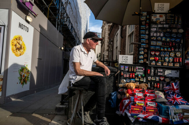a-souvenir-seller-shelters-under-hi-umbrella-along-piccadilly-central-london-as-a-mini-heatwave-causes-high-temperatures-in-the-capital
