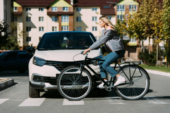woman-riding-bicycle-while-crossing-road-with-driver-in-car