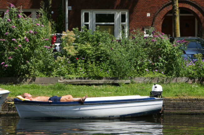amsterdam-netherlands-24th-june-2026-amsterdam-netherlands-june-24-a-local-enjoys-sunbathe-lies-under-boat-at-canal-during-heat-wave-where-temperatures-rose-up-to-35-degrees-celsius-on-j