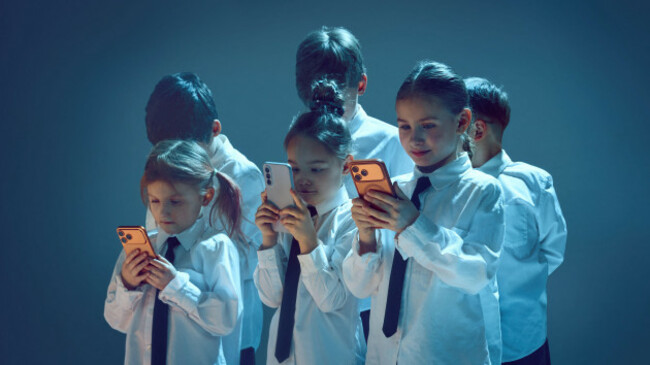 kids-in-suits-holding-smartphones-together-in-neon-studio